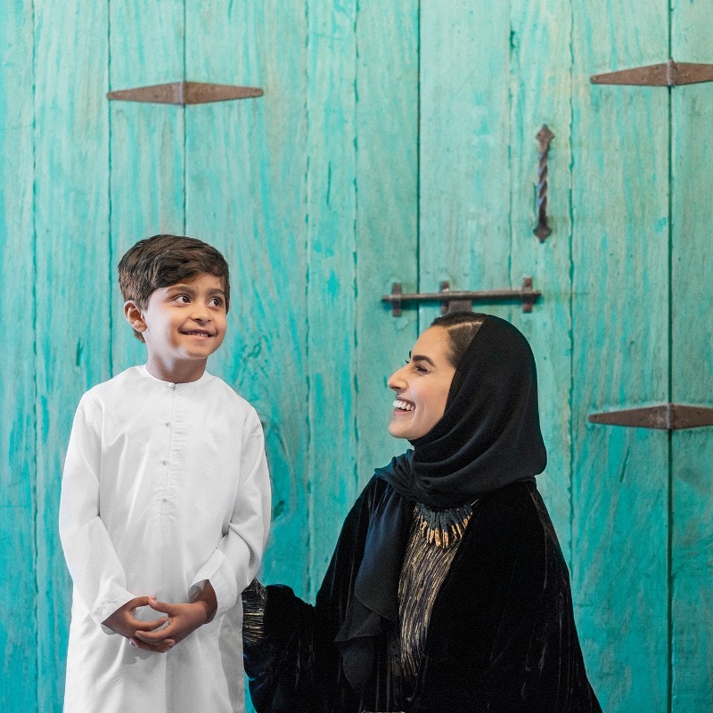طفل اماراتي مع امرأة اماراتية مبتسمان